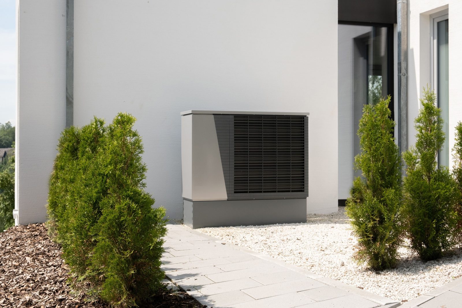Wärmepumpe im Vorgarten eines modernen Wohnhauses